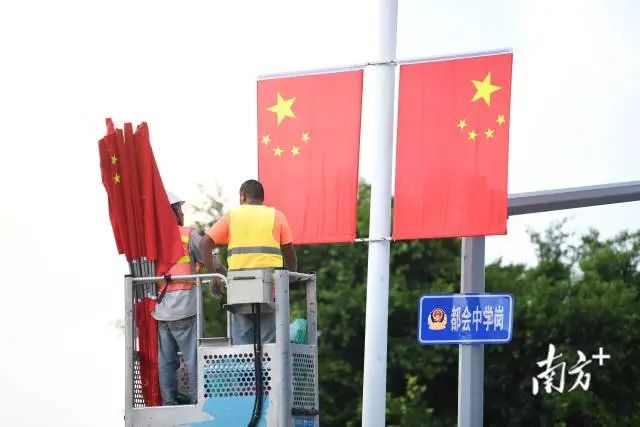 迎国庆,工作人员在市区主次干道的灯杆上升挂五星红旗。 南方+ 杨兴乐 拍摄 图片