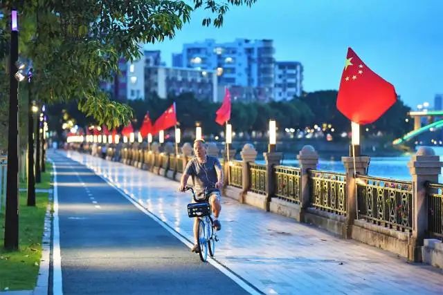 夜幕降临,蓬江河畔,釜山公园里红旗飘扬,市民群众在运动中观赏河滨优美风景。杨兴乐 摄 图片