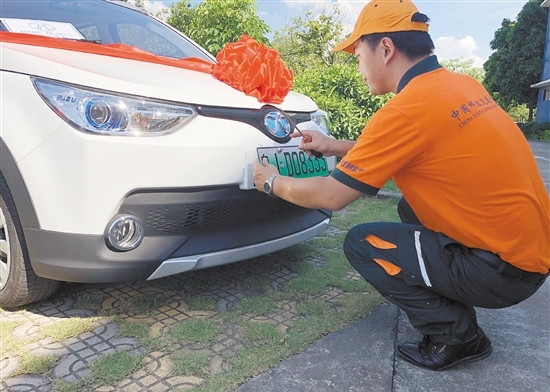 邮政工作人员为车主安装新能源汽车号牌.